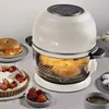 An air fryer is shown on a table with various food items around it, including a tart, bagels, and coffee. Voir les images du produit
