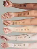 Multiple arms with different skin tones displaying swatches of makeup. Produktbild-Vorschau