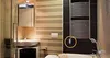 A bathroom with a sink, mirror, towel rack, and bathtub. A heating element is attached to the towel rack. Voir les images du produit