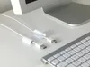 A close-up shot of white cable clips attached to white cables on a white desk, with a portion of a computer monitor and keyboard visible. Produktbild-Vorschau