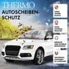 A white car is parked outdoors with a windshield cover on it. The background shows a transition from autumn to winter. Produktbild-Vorschau