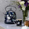A floral patterned electric kettle and mug are displayed on a marble countertop next to a vase of flowers and a jar of tea. Produktbild-Vorschau
