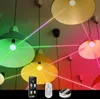 Smart LED pendant lights with colored light beams connecting them, a smartphone app interface, and a remote control. Produktbild-Vorschau