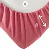 A close-up view of the elasticized edge of a pink fitted sheet, showing the gathered fabric and a measurement indicator. Produktbild-Vorschau