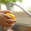 Hands washing an orange under a faucet in a sink. Produktbild-Vorschau
