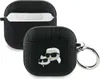 Two black AirPods cases are shown against a white background. One case is open, revealing the inside. The other case is closed and has a keyring attached. Both cases have a textured monogram pattern. The closed case features a cartoon illustration of Karl  Voir les images du produit