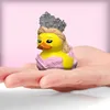 A small rubber duck figurine dressed as a princess, with a crown and gown, is held in a person's palm. Náhled obrázku produktu