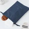 A dark blue drawstring bag with clothing items inside and a sock next to it. Anteprima dell’immagine prodotto