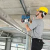 A construction worker is drilling into a concrete ceiling with a Bosch cordless rotary hammer drill. Produktbild-Vorschau