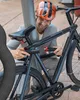 A man is locking his bicycle to a pole. Produktbild-Vorschau