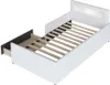 A white upholstered bed frame with a slatted base and an open drawer. Produktbild-Vorschau
