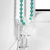 A close-up of a clear plastic bracket holding two turquoise beaded cords, likely for a window blind. Produktbild-Vorschau