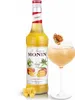 A bottle of Monin Mango syrup next to a cocktail, with mango cubes in the foreground. Podgląd zdjęcia produktu