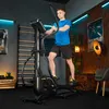 A man is exercising on an elliptical trainer in a home gym. Produktbild-Vorschau