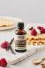 A bottle of vanilla extract is placed on a marble board with waffles, raspberries, and vanilla beans. Náhled obrázku produktu