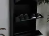 A black shoe cabinet with shoes on its shelves. Voir les images du produit
