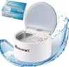 A white ultrasonic cleaner for dentures sits on a blue water splash graphic. A box labeled "Denture Ultrasonic Cleaner" is in the upper left corner. Produktbild-Vorschau