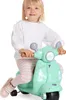 A young girl is riding a green toy scooter. Produktbild-Vorschau