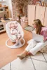 A woman is working on her laptop while a baby is in a baby bouncer in a nursery. Anteprima dell’immagine prodotto