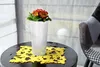 A white planter with red and yellow flowers sits on a dark table with a yellow placemat. Anteprima dell’immagine prodotto