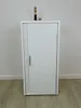 A white cabinet with a silver handle and a faucet on top, set against a white wall and a wooden floor. Podgląd zdjęcia produktu