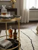 Makroaufnahme der spiegelnden schwarzen Glasplatte des Teewagens, auf der sich der goldene Stahlrahmen und das Umgebungslicht edel reflektieren._#sku_SAFWL6.000# Produktbild-Vorschau