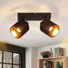 A black ceiling light fixture with two adjustable spotlights, each with a gold interior, mounted on a white ceiling. Voir les images du produit