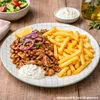 A plate of food with meat, fries, and a side salad, set on a wooden table. Náhled obrázku produktu
