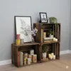 Wooden crates stacked and used for storage and decoration, with books, plants, candles, and framed pictures. Náhled obrázku produktu