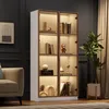 A well-lit display cabinet filled with decorative items and books, placed in a living room setting next to a sofa and curtains. Náhľad obrázku produktu