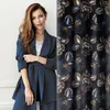 A woman wearing a blue suit is shown next to a fabric swatch with a floral pattern. Produktbild-Vorschau