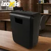 A black paper shredder sits on a wooden desk in an office setting. Produktbild-Vorschau