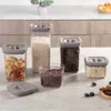 A set of five clear food storage containers with gray lids, filled with various dry goods like pasta, rice, beans, and oats, arranged on a countertop. Produktbild-Vorschau
