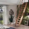 A wooden staircase with a metal railing in a room with a large window, plants, and framed pictures. Produktbild-Vorschau