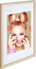 A framed picture of a woman with a bow hairstyle and bright makeup, set against a polka-dot background. Produktbild-Vorschau
