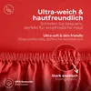 A close-up of a red fabric, likely a bedsheet, with text overlays highlighting its features. Produktbild-Vorschau