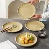 A table setting with plates, cutlery, and food, with a person holding a plate. Produktbild-Vorschau