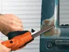 A person is using an orange power file tool to sand a blue surface, likely a car door, revealing rust underneath. Náhľad obrázku produktu