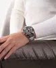 A person wearing a watch and a white sweater, sitting down. Voir les images du produit