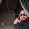 A man wearing sunglasses is holding a radio in a truck cabin. Anteprima dell’immagine prodotto