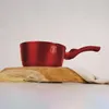 A red saucepan is placed on a wooden board with some fabric. Náhled obrázku produktu