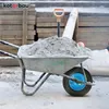 A wheelbarrow filled with cement and a shovel, on a construction site. Voir les images du produit