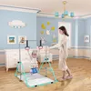A child is using a foldable gymnastics bar indoors, with a woman supervising. Voir les images du produit