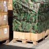 Cardboard boxes are stacked on wooden pallets, covered by a camouflage tarp. Produktbild-Vorschau