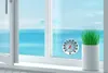 A thermometer attached to a window with a view of the ocean and mountains. Anteprima dell’immagine prodotto