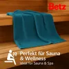 A teal towel is draped over wooden benches in a sauna. Produktbild-Vorschau
