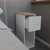 A white bedside table with an open drawer and a wooden top is placed next to a bed. Náhled obrázku produktu
