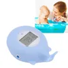 A baby is taking a bath with a mother watching, next to a blue whale-shaped bath thermometer. Produktbild-Vorschau