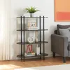 A black, multi-tiered shelving unit filled with decorative items, situated in a living room next to a sofa. Náhled obrázku produktu
