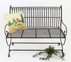 A metal garden bench with a decorative pillow and a potted plant. Produktbild-Vorschau